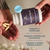 Person holding a container of colostrum with text highlighting benefits on a neutral background