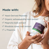 Person holding a supplement bottle with ingredients listed on a beige background