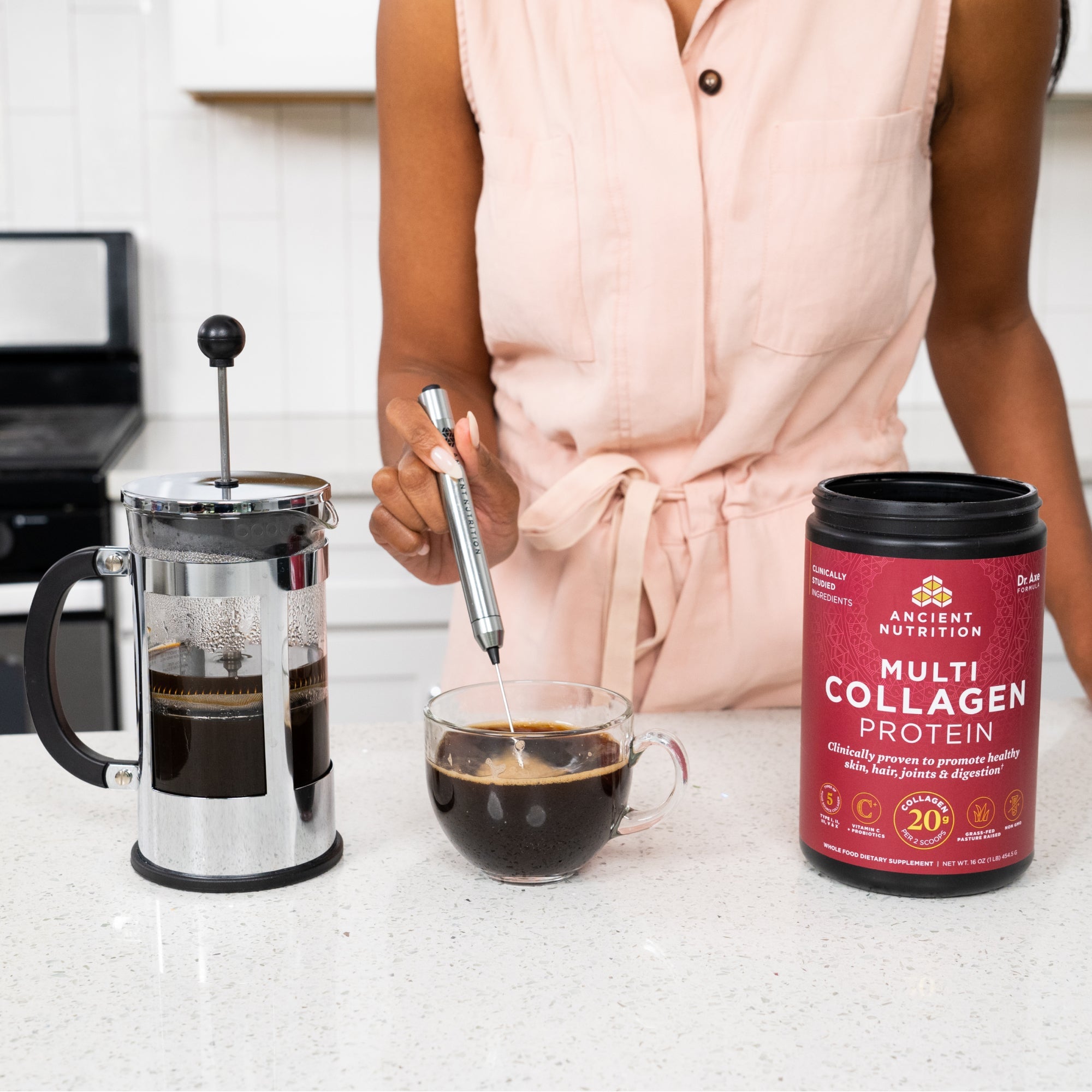 woman using a frother to mix coffee