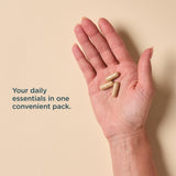 A close-up of a person's open palm holding three beige capsules, with the text 'Your daily essentials in one convenient pack.' on a warm beige background.