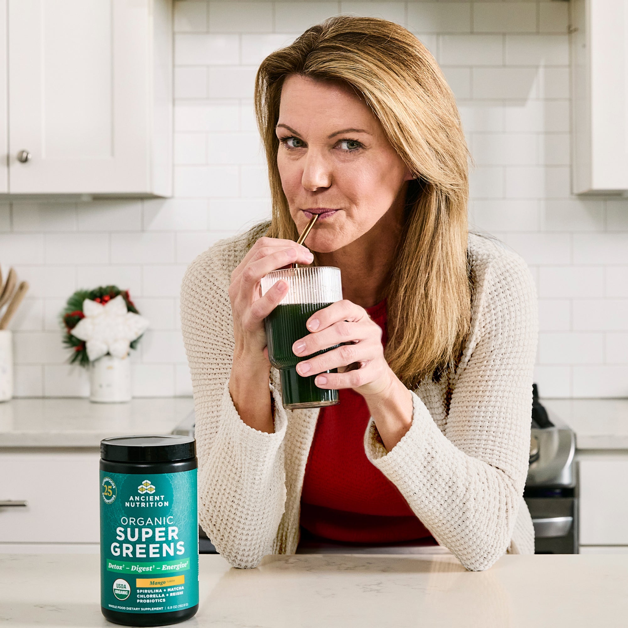 a woman drinking supregreens mango