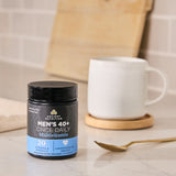 Men's 40+ Once Daily Multivitamin container on a kitchen counter with a mug and spoon.