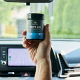 Hand holding a supplement container in a car interior