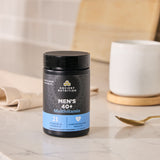 Men's 40+ Multivitamin container on a marble surface with a cup and spoon in the background