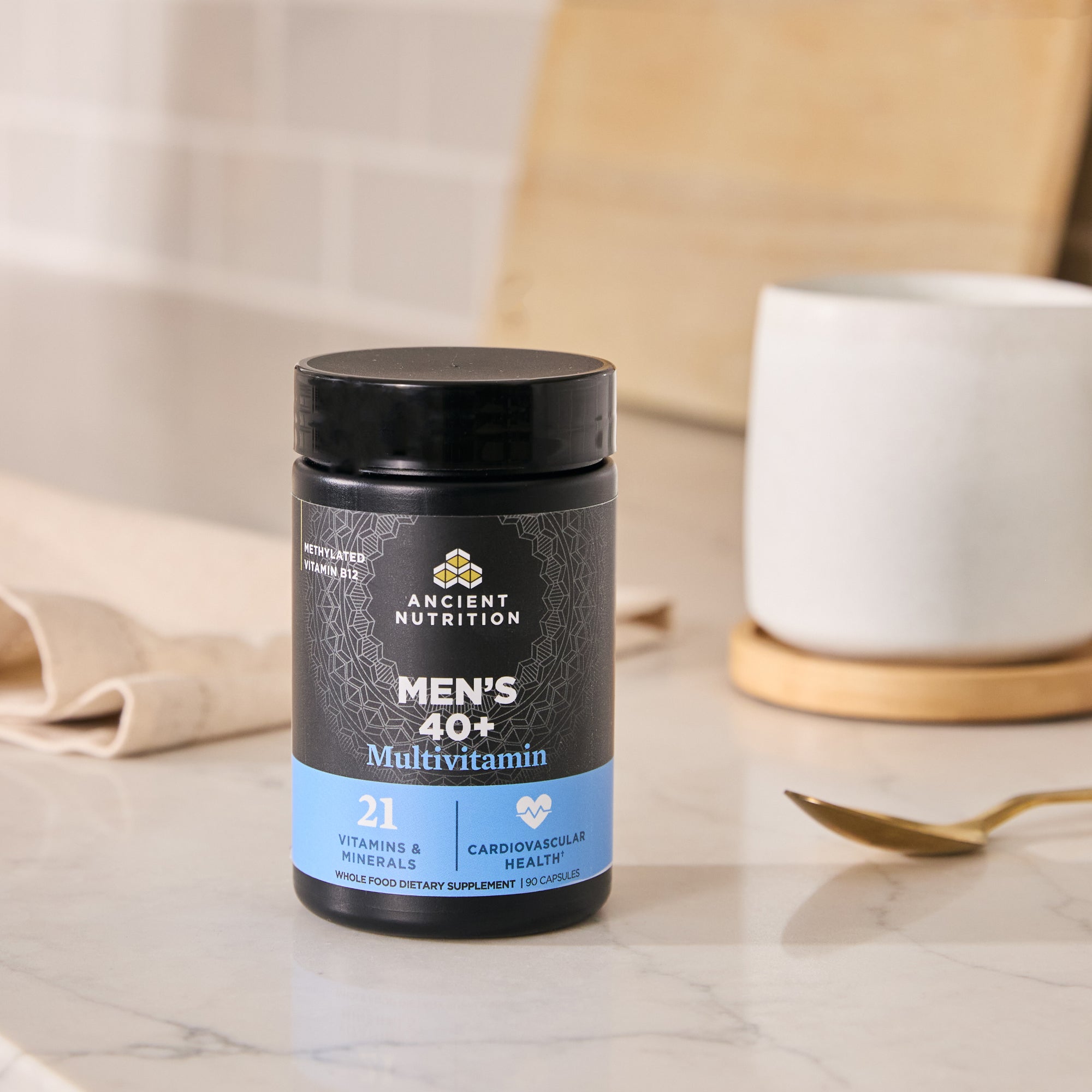 Men's 40+ Multivitamin container on a marble surface with a cup and spoon in the background