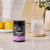 Ancient Nutrition Women's 40+ Multivitamin bottle on a kitchen counter with lemons and a glass of water in the background.