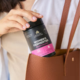 Person holding a container of Ancient Nutrition Women's Fermented Multivitamin.