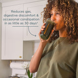Woman drinking from a glass with text about digestive benefits in a kitchen setting