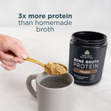 Person adding bone broth protein powder to a mug with a container of the product in the background.
