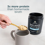 Person adding bone broth protein powder to a mug with a container of Ancient Nutrition Bone Broth Protein in the background.