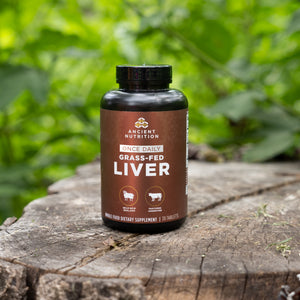 a bottle of Grass-Fed Liver Once Daily Tablets on a tree stump