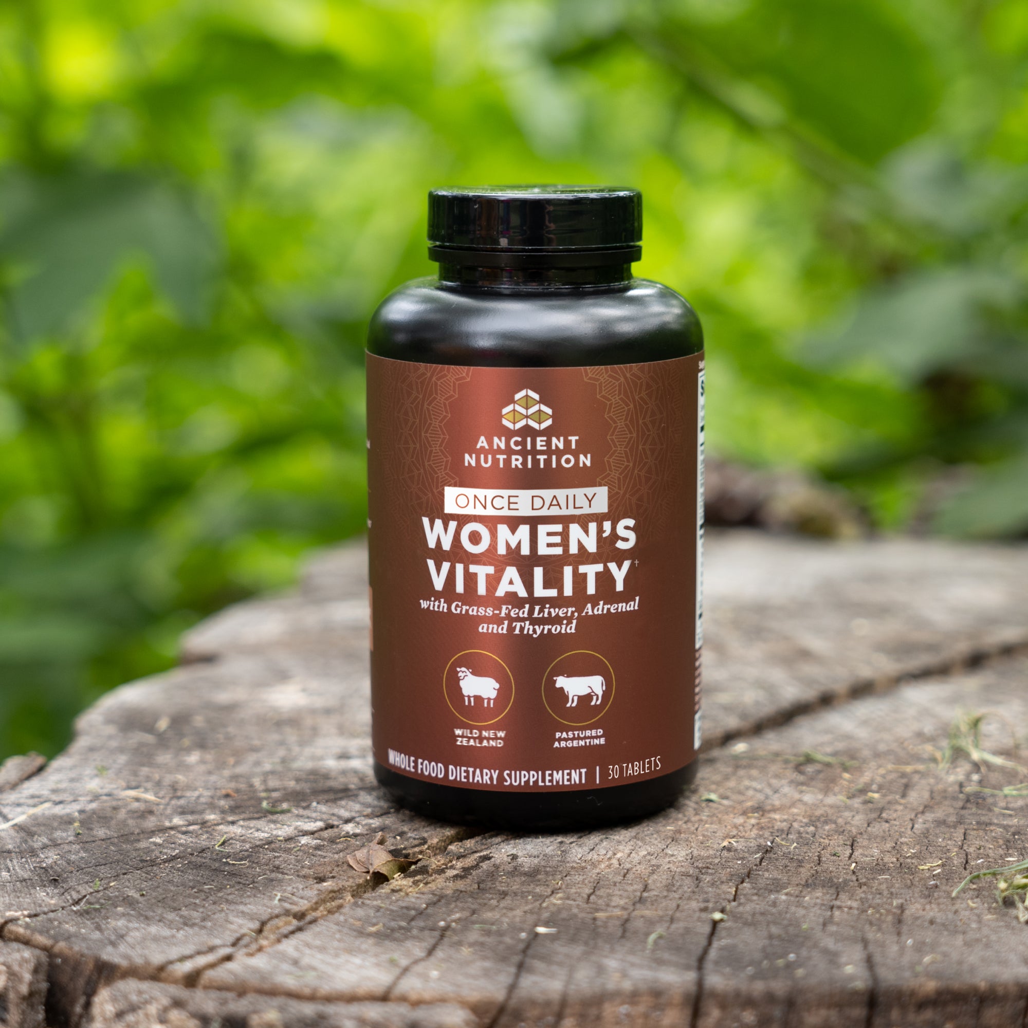 a bottle of Women's Vitality Once Daily Tablets on a tree stump