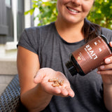 a woman holding a bottle of Grass-Fed Liver capsules