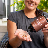 woman with a bottle of grass-fed liver capsules and capsules in hand