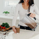 girl pouring smoothie in glass cup