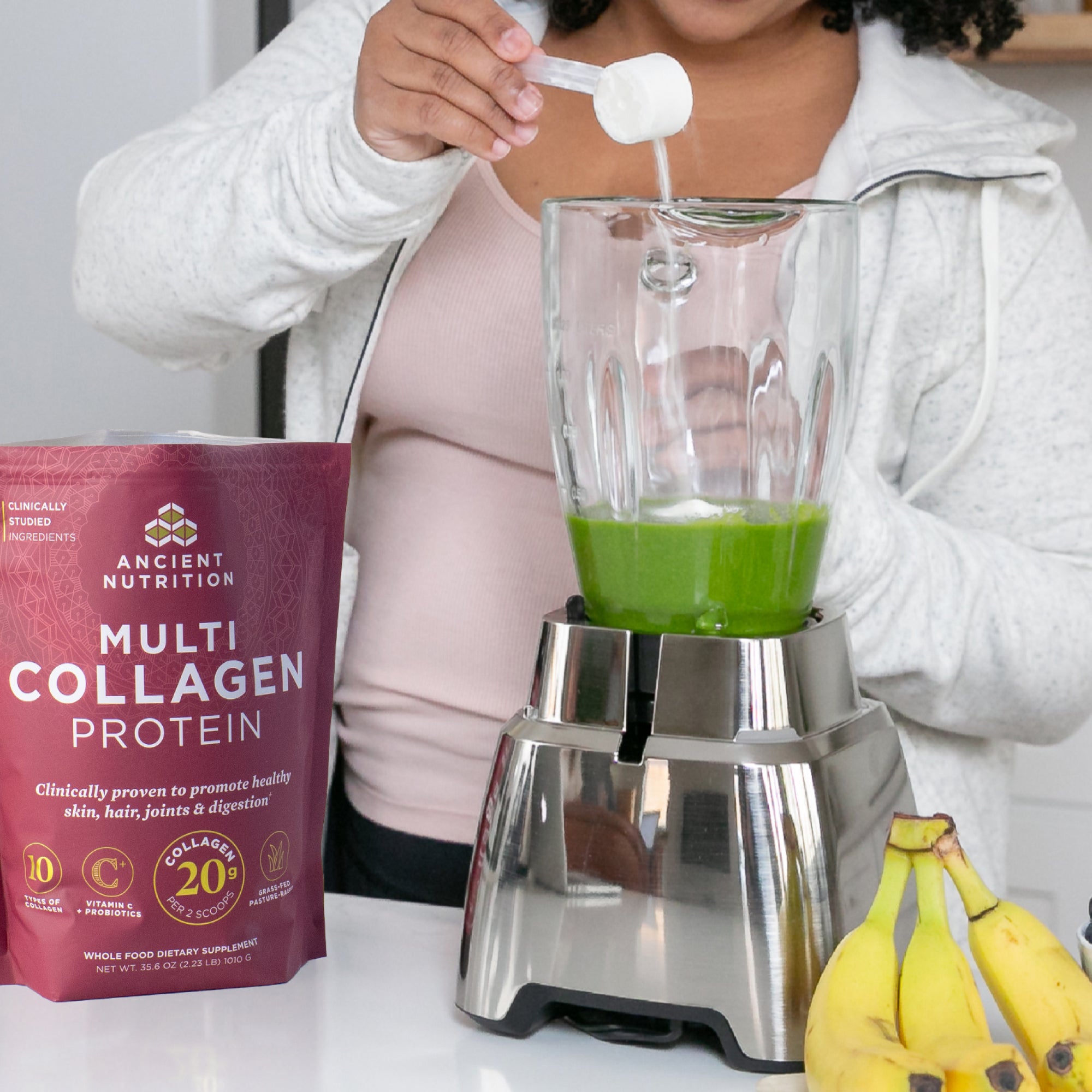 a person scooping collagen into a green smoothie