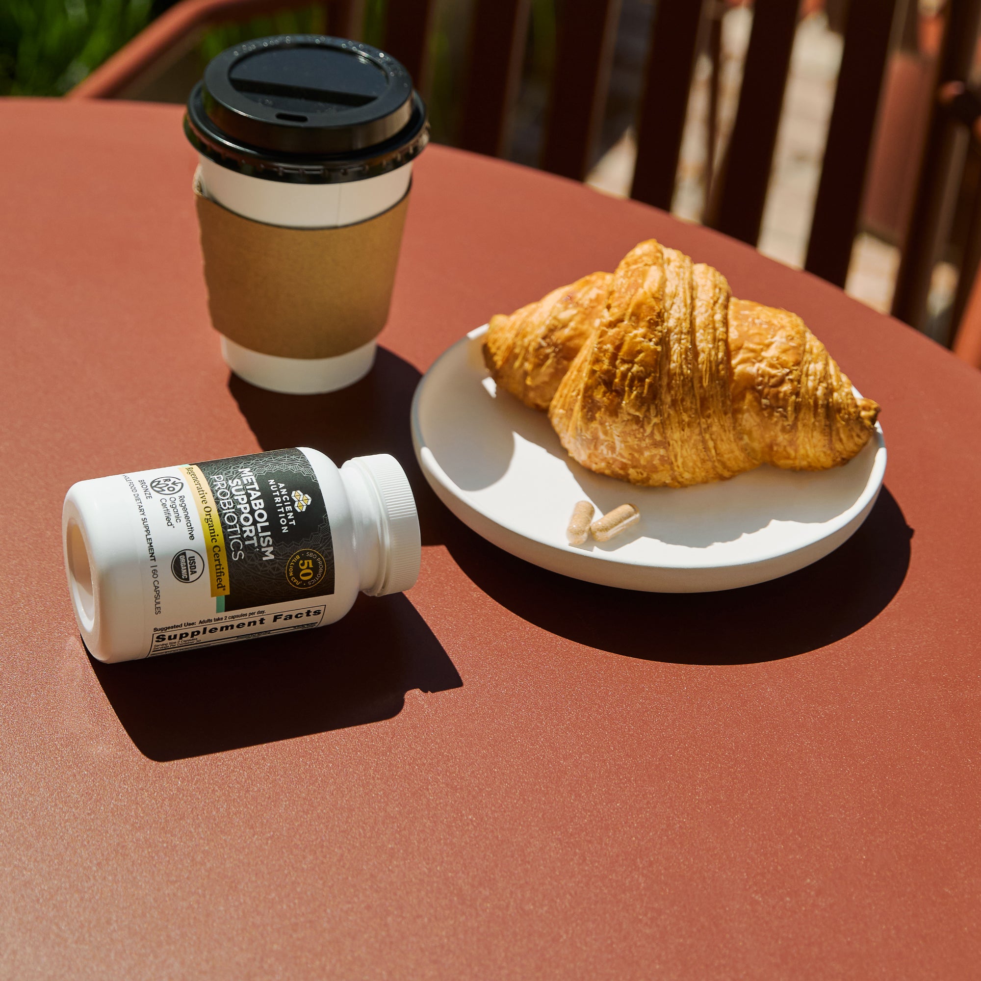 a bottle of Regenerative Organic Certified® Metabolism Support Probiotics Capsules (60 Capsules) next to a croissant 