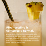 A clear glass filled with an iced beverage and a dark metal straw, garnished with a pineapple slice, with overlaid text explaining fiber settling. 