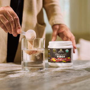 a person adding a scoop of Organic Fiber Powder Raspberry Lemonade Flavor (30 Servings) to a glass