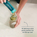 Person adding a Organic SuperGreens package to a bottle on a white surface