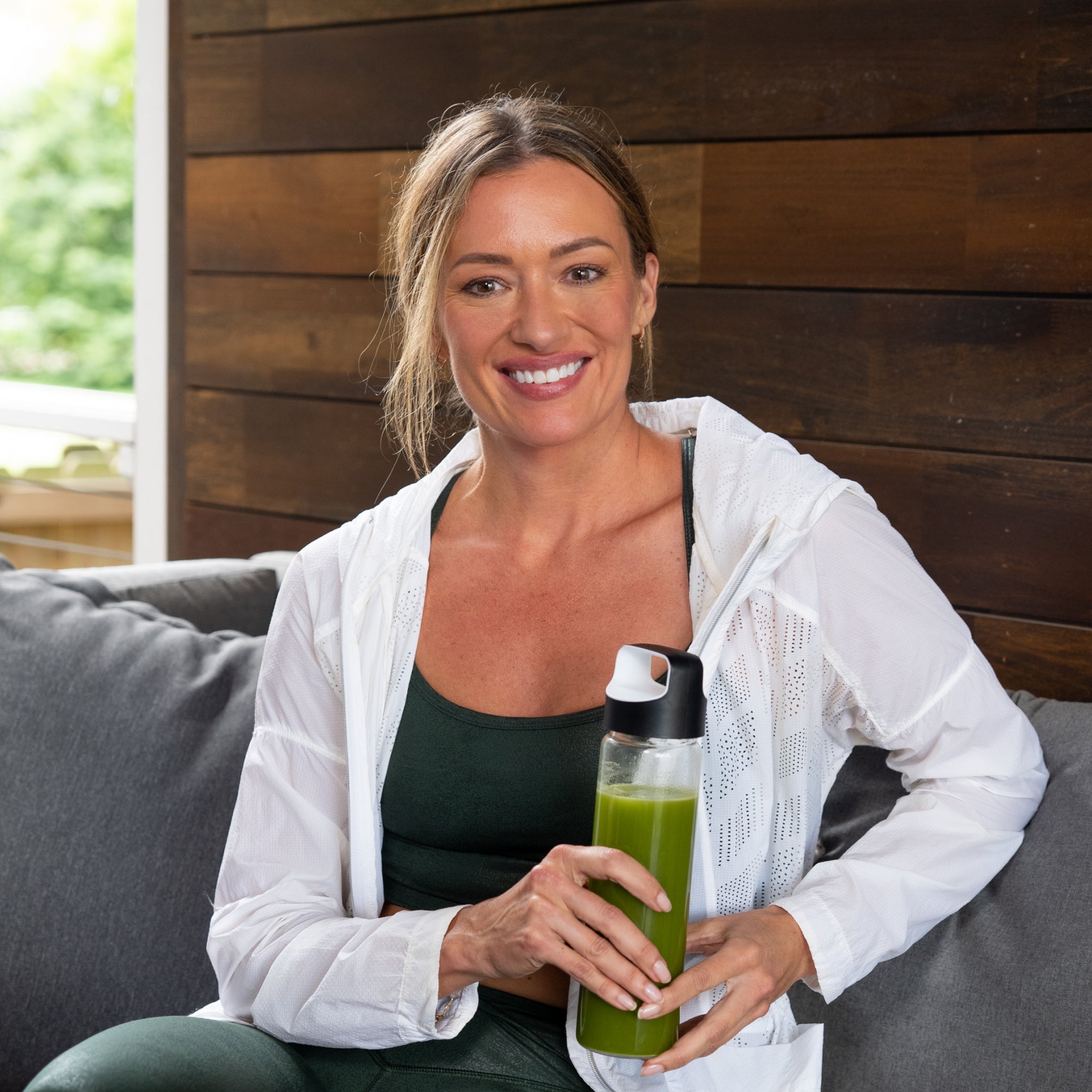 a woman holding a bottle of green juice