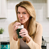 a woman drinking Organic SuperGreens Powder Greens Flavor (12 Servings)