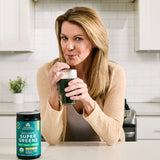 a woman drinking a glass of organic supergreens