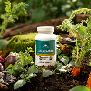 bottle of Regenerative Organic Certified™ SuperVeggies in a vegetable garden