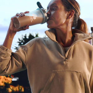 a woman drinking Whey Protein Powder Chocolate Peanut Butter from a shaker bottle