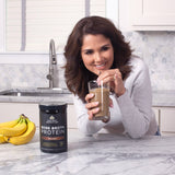 woman drinking bone broth protein chocolate out of glass