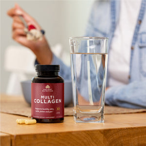 bottle of multi collagen capsules  next to a glass of water