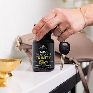 A person grabbing a bottle of SBO Probiotics Trinity Capsules on the go