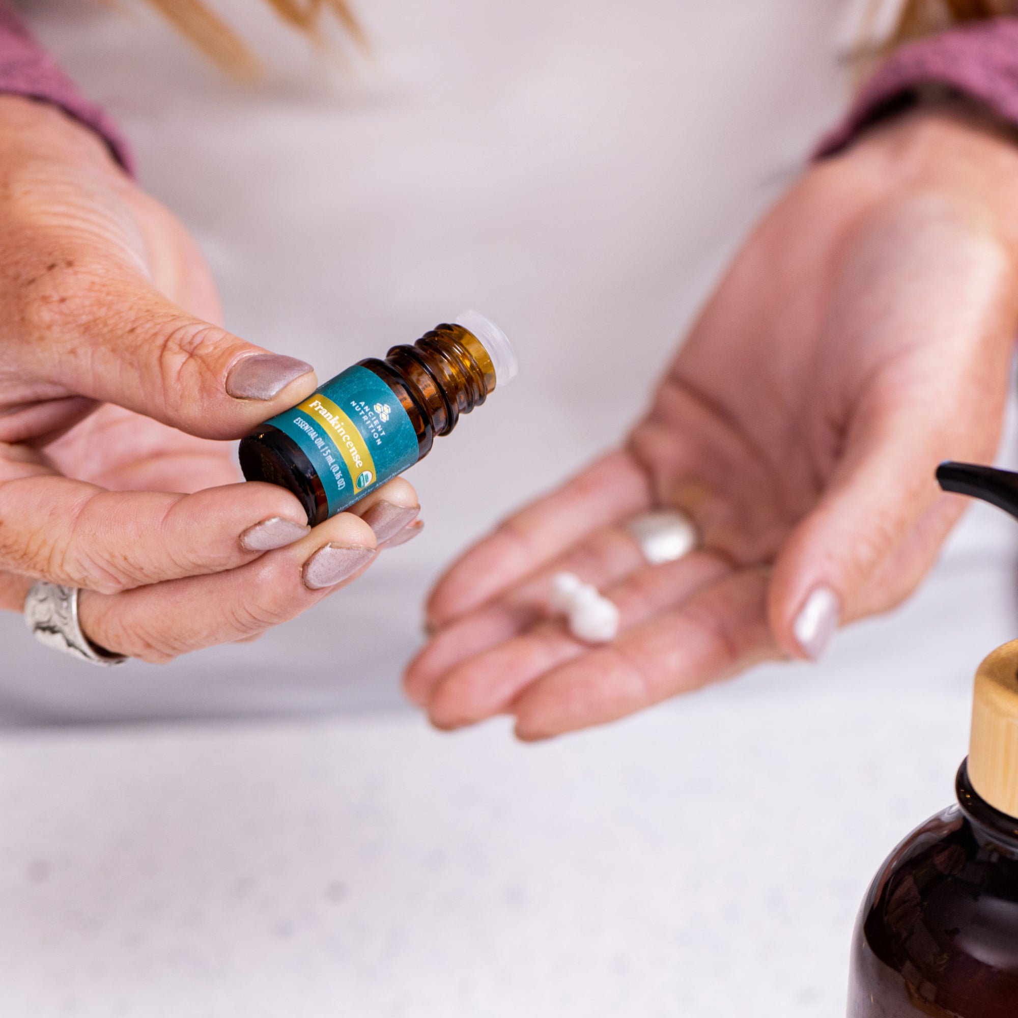 a person putting Frankincense Essential Oil in a carrier lotion in their hands