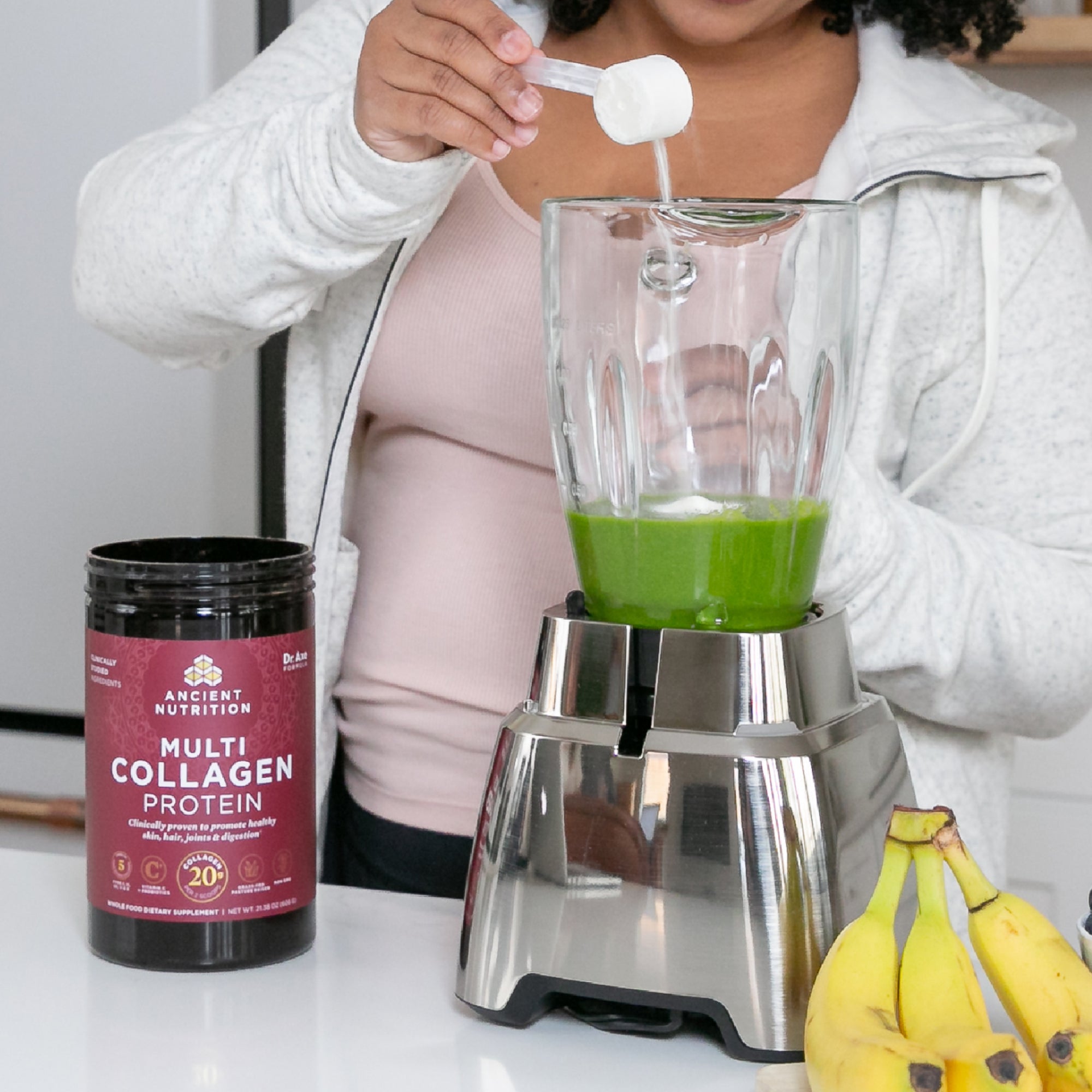 girl pouring collagen in green smoothie