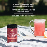 multi collagen protein strawberry lemonade bottle next to drink pitcher in grass